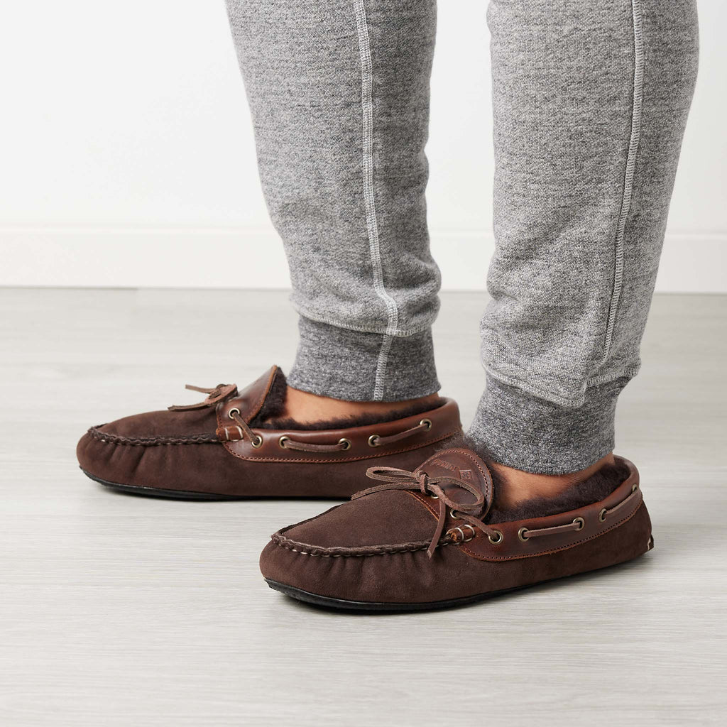 Men’s Fireside Slippers in Chocolate, on man, moccasin construction, twinface shearling, perimeter lacing, Vibram soles, Quoddy